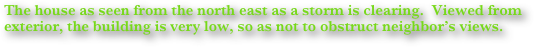 The house as seen from the north east as a storm is clearing.  Viewed from exterior, the building is very low, so as not to obstruct neighbor’s views.